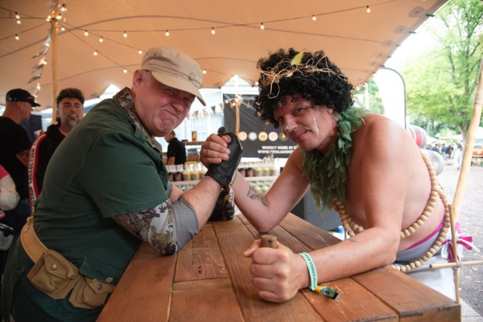 Festivalfans in Kostümen beim Armdrücken